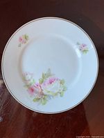 Front of porcelain plate showing rose motif and gold rim