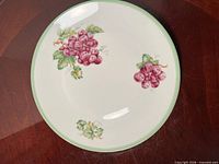 Top view of porcelain plate showing grape design and green rim