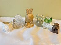 Group shot of the five owl figurines displaying ceramic, frosted glass, carved wood, and two clear art-glass pieces