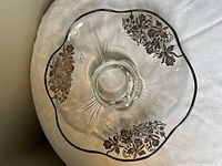 Top view showing platter shape, embedded silver floral pattern, scalloped rim