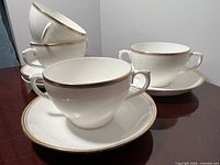 Group of soup bowls and saucers showing quantity, shape, and gold trim