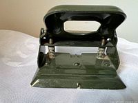 Front view of green metal 2-hole punch showing handle, springs and punch bar