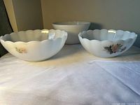 Front view of three milk glass bowls showing two scalloped bowls with rose decals and one plain bowl