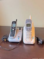 Both VTech handsets on their charging cradles with attached cords and power adapter visible