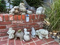 Group view of eleven concrete animal statues on brick ledge and walkway