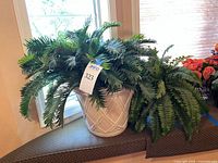 Large faux fern in white planter on window seat