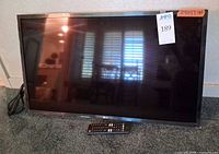 Front view of LG 32-inch TV on carpet with remote and power cord visible