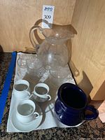 Grouped view of all pitchers, cups and saucers on counter