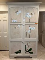 Front view of cream armoire with hand-painted orchid design