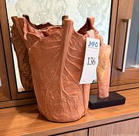 Leaf motif terracotta vase beside figural sculpture