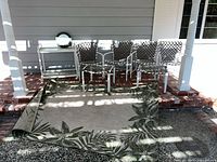 Outdoor rug unrolled with furniture stacked on brick patio
