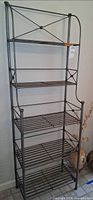 Full view of pewter-tone iron baker’s rack showing five shelves and frame