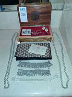 Overview showing inlaid music box open with jewelry inside, faux pearl strands on sides, evening clutch and rhinestone bracelets