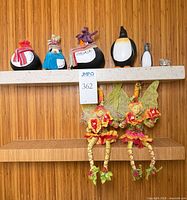 Shelf with three stone penguins, resin penguin, glass seal and two hanging Mark Roberts fairies