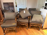Front view of group of upholstered wood dining chairs with casters and loose pillows