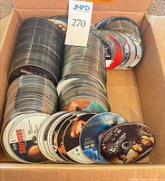 Cardboard box filled with stacks of loose DVD discs
