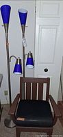 Two brushed metal floor lamps beside Polywood chair, lamps off