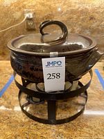 Full view of fondue pot with lid on metal stand