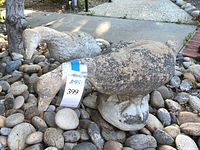 Two concrete geese statues on river rock ground