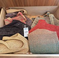 Drawer containing multiple raffia purses showing variety of colours and textures
