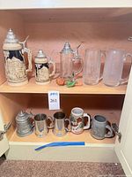 Cabinet view showing all ten steins and mugs on two shelves