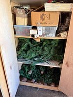 Cabinet shelves with boxes of pinecones, faux berries, floral supplies and stacked artificial greenery