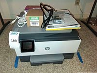 Overall view of HP OfficeJet Pro 9015e printer with accessories stacked on top