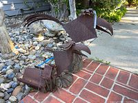 Overview of two rusted metal bird sculptures and birdhouse on patio