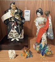 All items in lot – two Hakata dolls, two clay figurines, carved pendant
