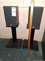 Pair of JBL ARC10 speakers on stands, front view with ruler showing overall height