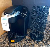 Keurig brewer beside black metal pod rack on countertop