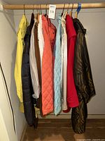 Nine assorted coats and jackets hanging on rod