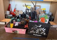 Overview of two containers filled with irrigation supplies, hose nozzles, sprinkler heads, PVC fittings, drip stakes.