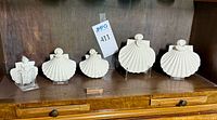 Five shell angel figurines on shelf with acrylic stands