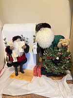Two Santa figurines on wooden bases with small gift box visible