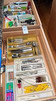 drawer with trays of stainless flatware and utensils