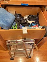 Drawer containing orthopedic boot, braces, monitors, bandages, cushion with walker and cane in foreground