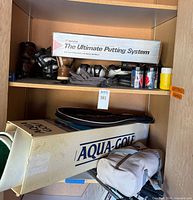 Shelf with putting system box, golf shoes, racquetball gear, Aqua-Golf box, golf club bag