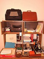 Overall lot showing two briefcases on shelf with assorted paper goods
