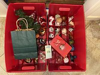 Two red storage bins containing assorted ornaments, gift bag visible