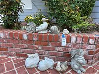 All eight concrete statues arranged on brick ledge and patio