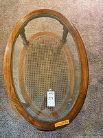 Top view of oval wood frame with glass inset and cane shelf