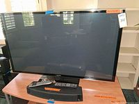 Front view of Panasonic plasma TV on stand with remote placed on table