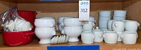 Shelf view showing red mini casserole dishes, stacks of white soup bowls, ramekins and condiment pots