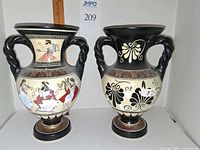 Front view of both ceramic vases showing painted Greek scenes and twisted handles