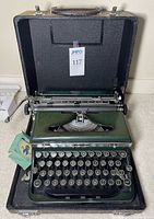 Typewriter seated inside open carrying case with booklet visible