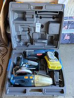 Open plastic carry case showing circular saw, jigsaw, vacuum, charger