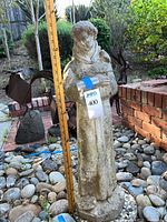 Full view of concrete Saint Francis statue with measuring stick showing height
