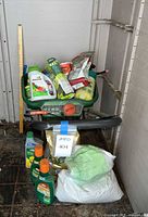 Spreader loaded with assorted lawn-care products, weed-killer bottles on floor, large white fertilizer bag