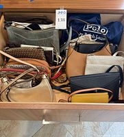 Drawer view showing multiple handbags, wallets and Polo dust cover